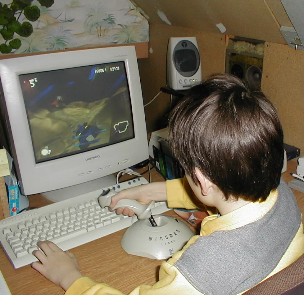 Jurgen als kind aan een computer met een joystick, een racegame op het scherm